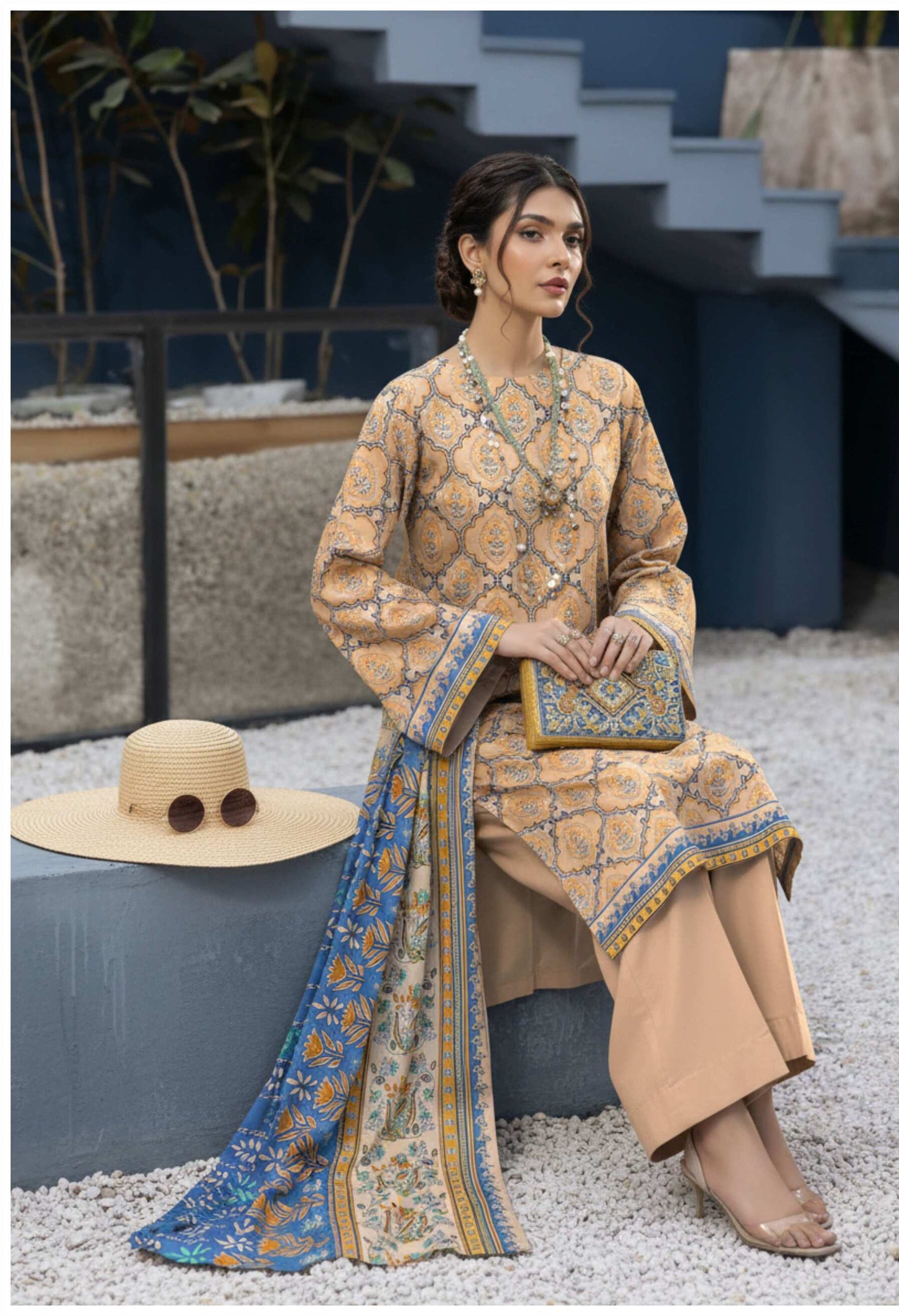 Elegant beige printed 3-piece lawn suit with matching blue printed dupatta, featuring detailed designs and lightweight fabric.